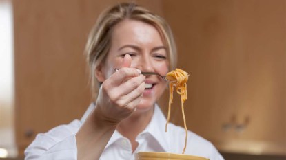 Woman-about-to-eat-a-forkful-of-spaghetti-while-wearing-a-white-shirt