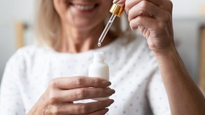 close up of mature woman opening a bottle of extract, squeezing the dropper with her hand