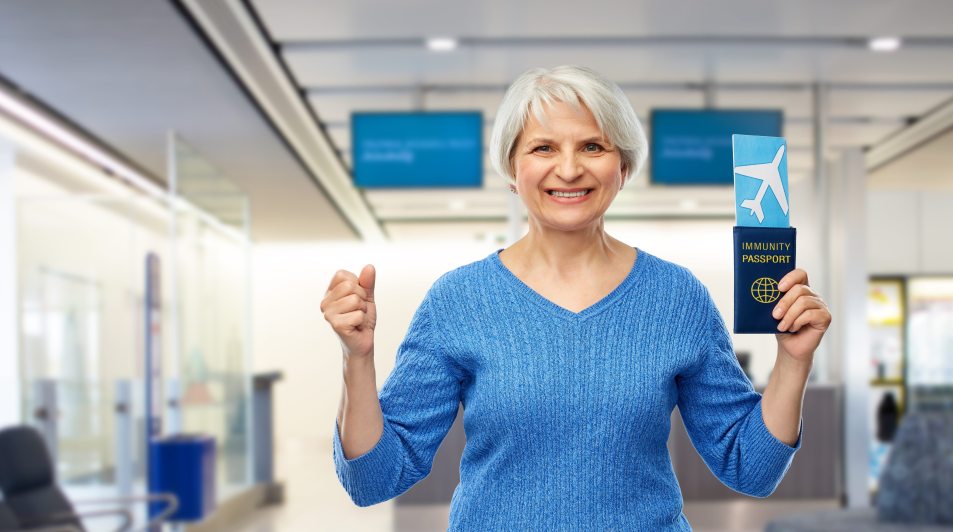 mature woman at airport, smiling, holding passport, hand in the air