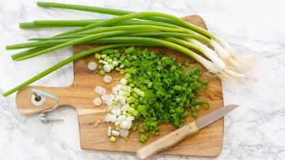 Sliced scallions on a wooden cutting board as part of a guide on how to store them