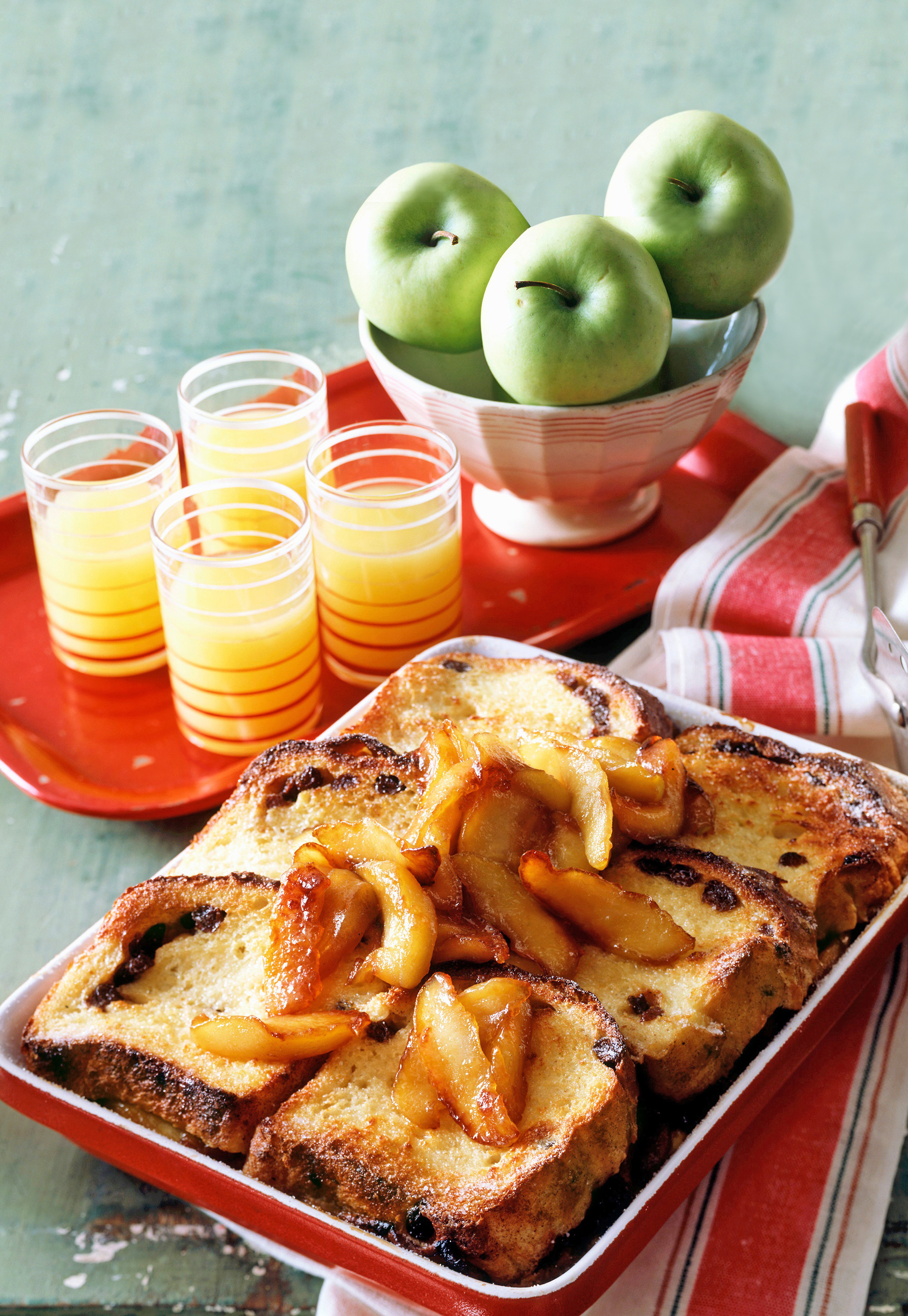 baked apple French toast on a plate next to glasses of orange juice