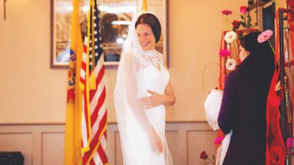 military bride turning back, smiling, wearing her perfect wedding dress from the donation of 500 wedding dresses