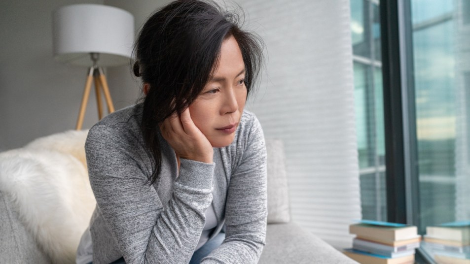 Sad Asian mature woman lonely at home self isolation quarantine for COVID-19 Coronavirus social distancing prevention. Mental health, anxiety depressed thinking senior chinese lady.