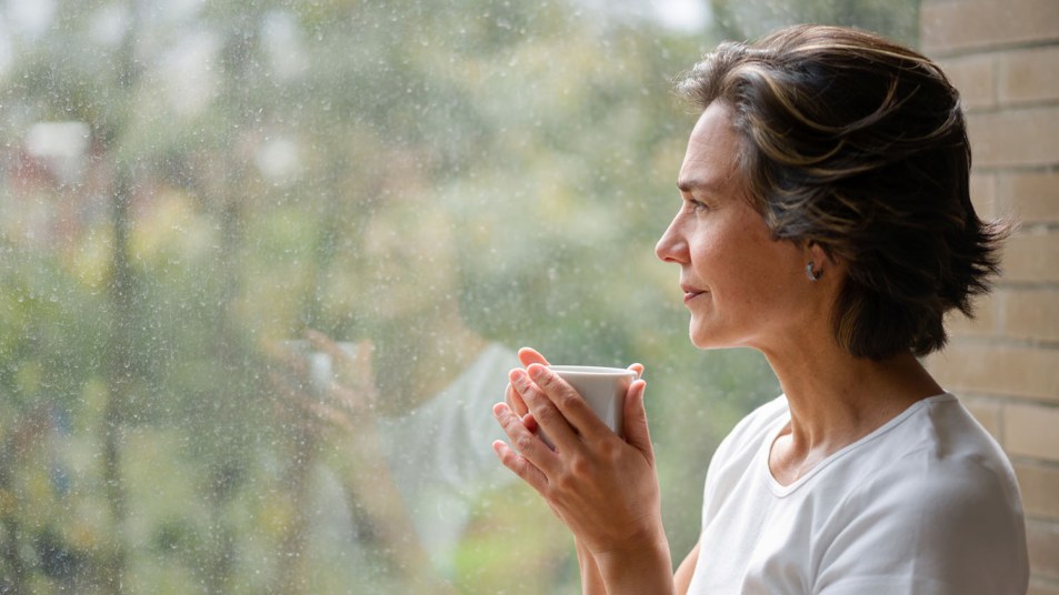 Woman drinking a cup of coffee while looking out of the window