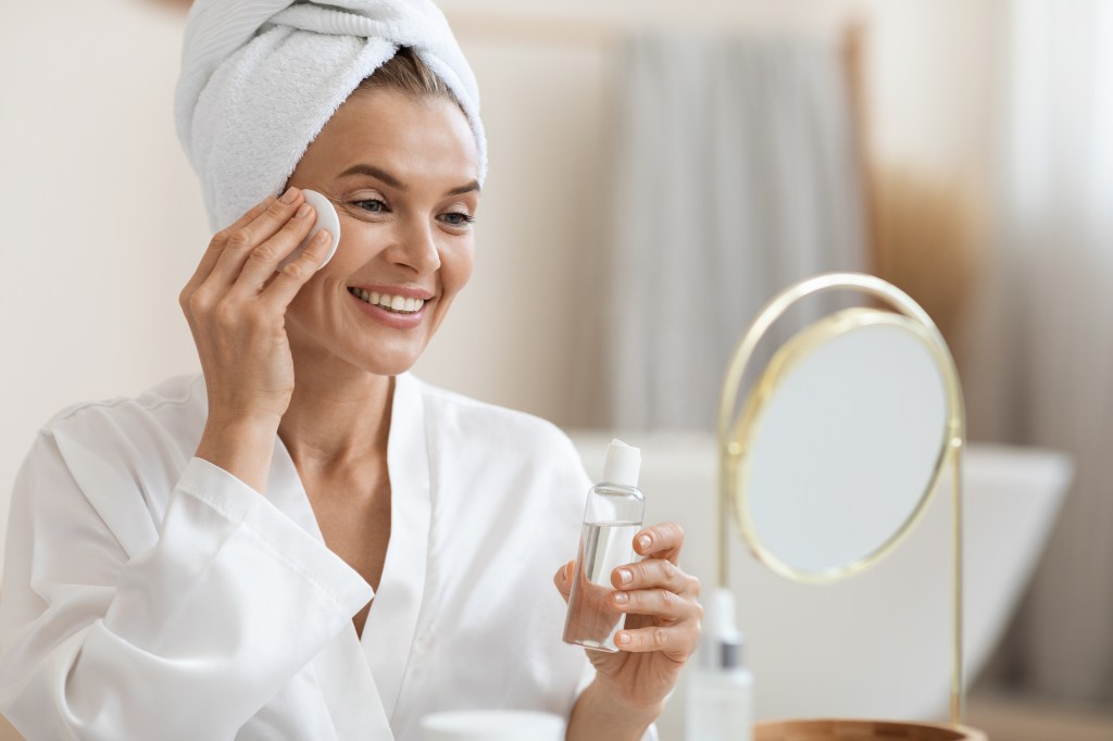 woman using chemical exfoliant on face with cotton pad