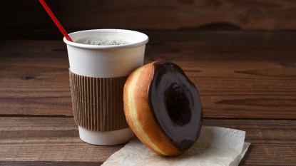 free coffee in to-go cup and a chocolate frosted doughnut, for National Coffee Day