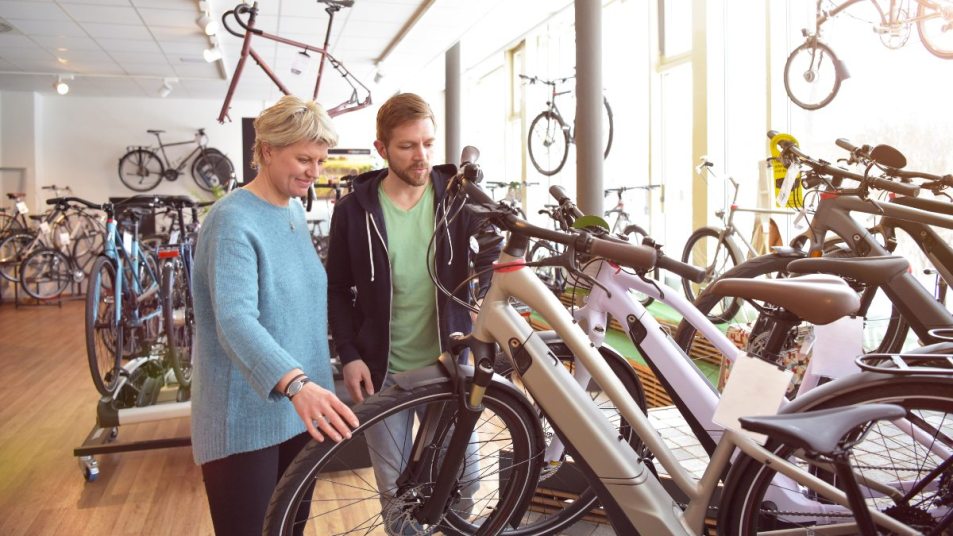 mature woman in a bike store looking to purchase an e-bike, salesman helping her