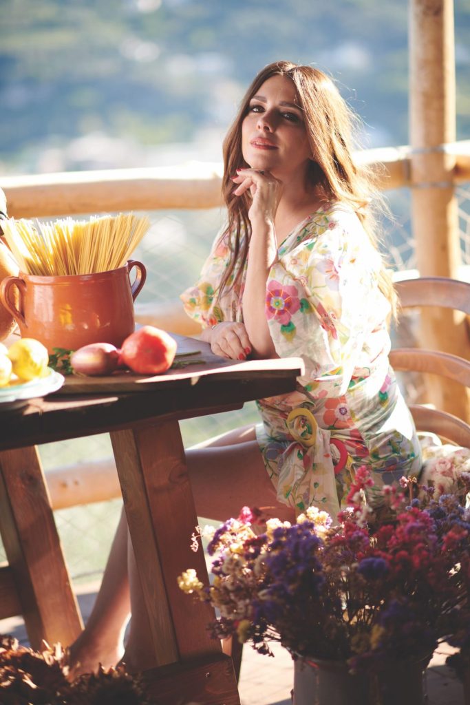 Nadia Munno sitting at a table with pasta and flowers.