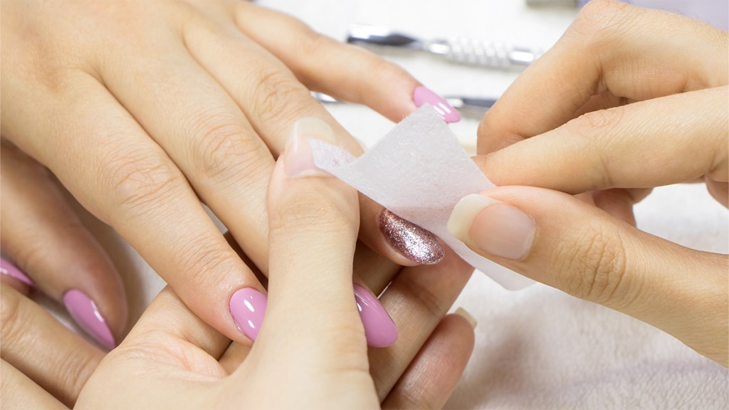 Genius uses for dryer sheets: woman using a dryer sheet to remove nail polish