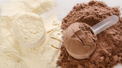 vanilla and chocolate protein powders in measuring cups against white background