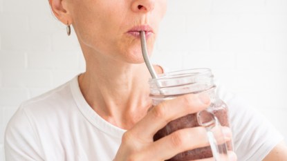 mature woman sipping out of a metal straw causing wrinkles around her mouth