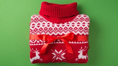 A colorful Christmas sweater tied with a red ribbon