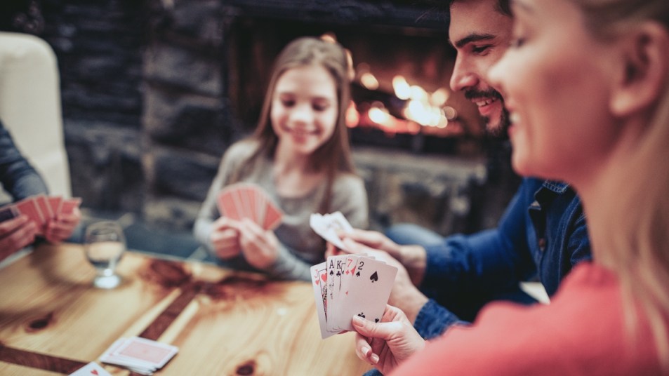 Young family playing card game at home