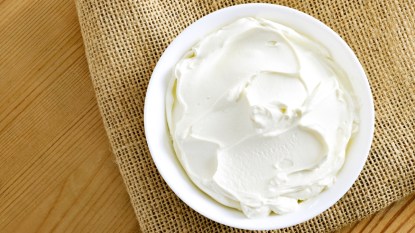 Cream cheese, quark or yogurt in a white bowl. Dairy product, healthy eating theme. wooden table background.