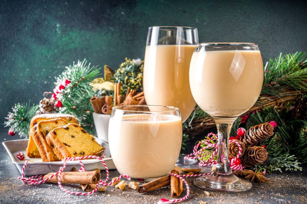 Traditional Christmas egg dairy drink with spices, in different glasses. Eggnog cocktail, Cola de mono, Crème de Vie (Cream of Life) beverage. Dark background with Christmas decor