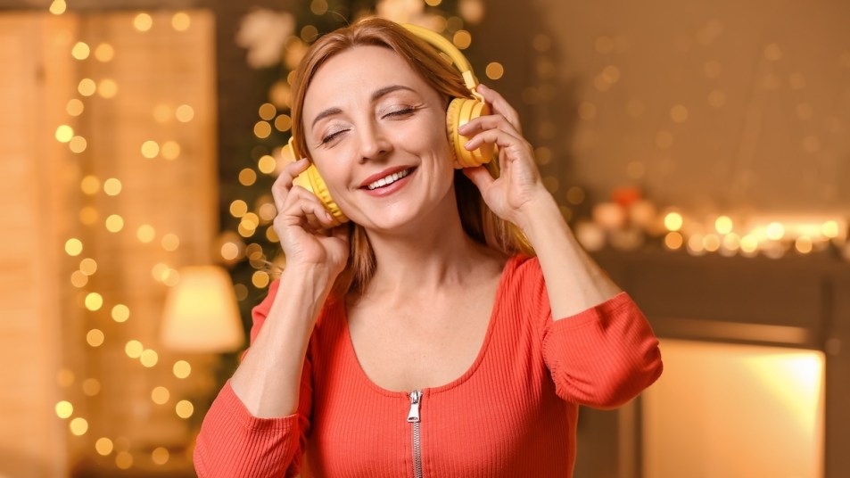 Woman with headphones in front of holiday lights