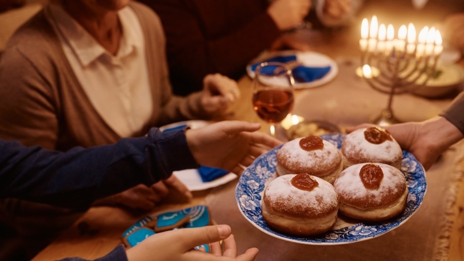 Jelly donuts, cookies, and wine being served on Hanukkah dinner table with menorah