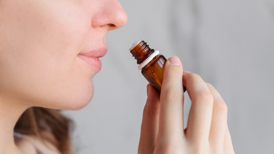 woman testing her sense of smell with essential oil, concept for covid loss of taste and smell