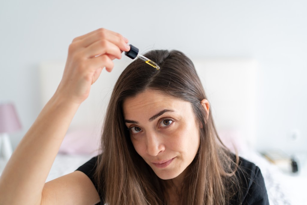 Woman applying a scalp treatment to help achieve a healthy scalp