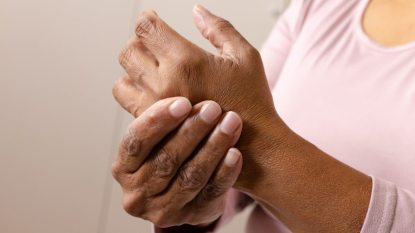 mature woman rubbing her tingling hands, symptom of menopause