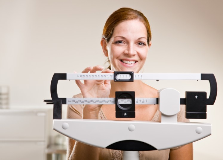 Woman weighing herself and smiling