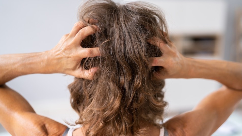Woman massaging her head, seen from back