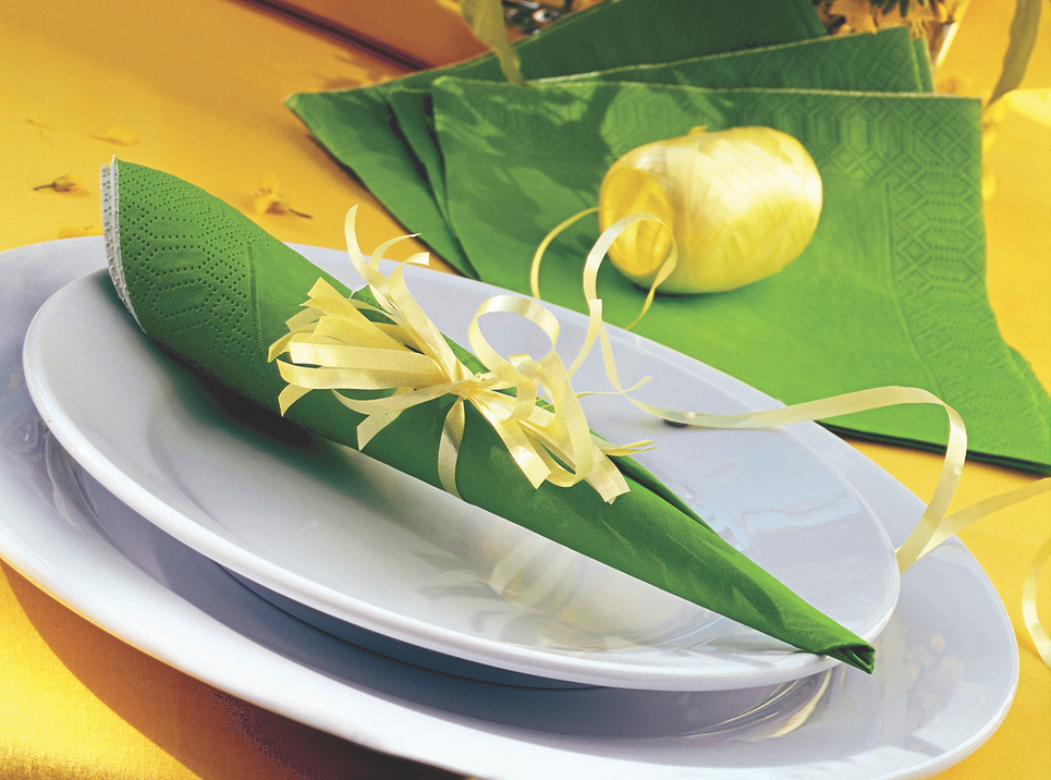 Utensils in green napkin wrapped with yellow ribbon