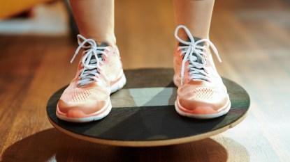 close up of a woman's orange sneakers on a circular balance board