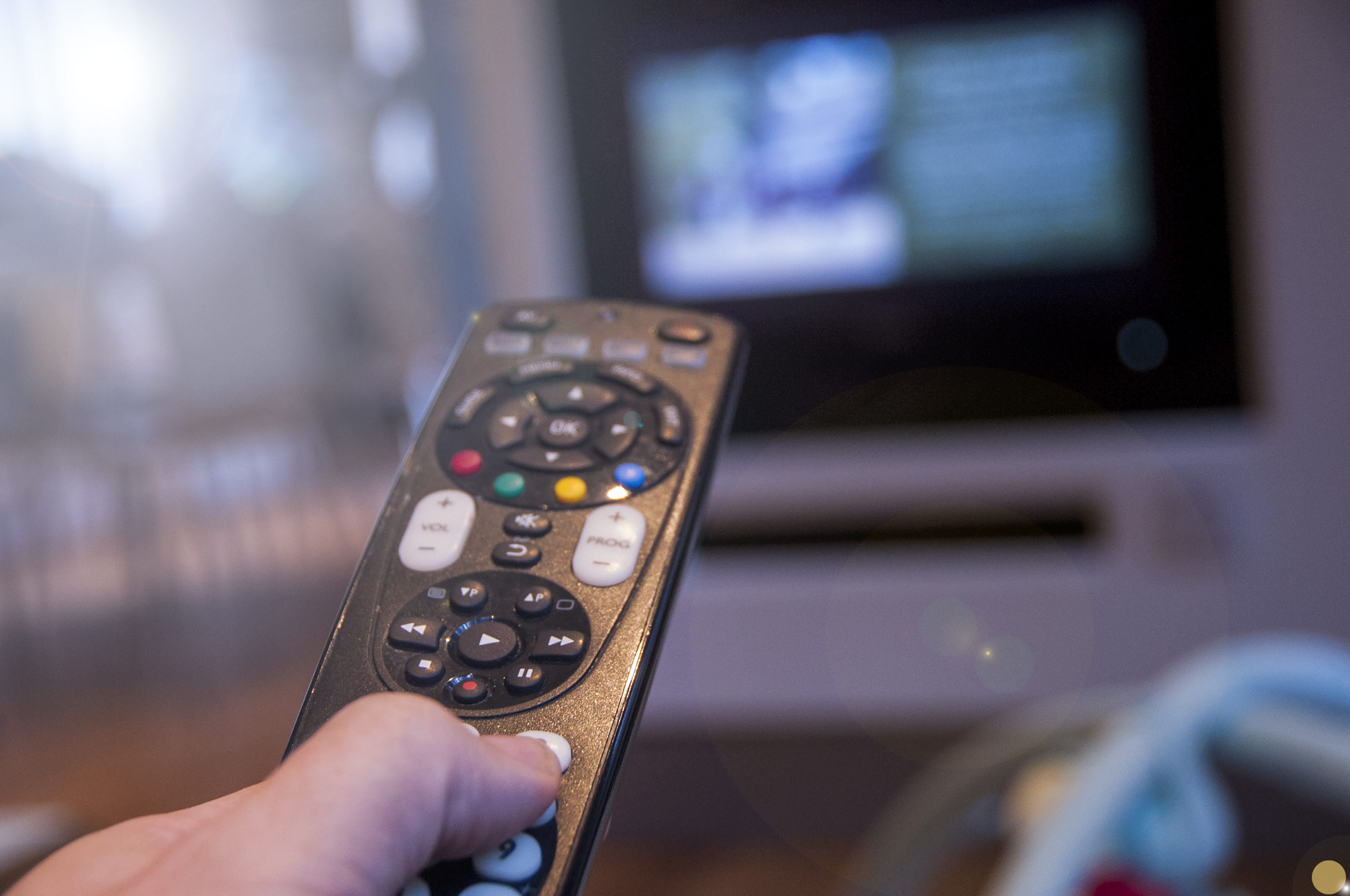 close up of person holding a remote in front of a TV