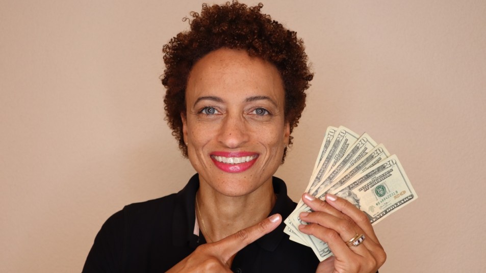 mature woman smiling, holding cash and pointing to it