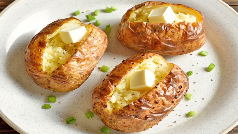 Baked potatoes topped with butter as part of a guide on how to reheat a baked potato