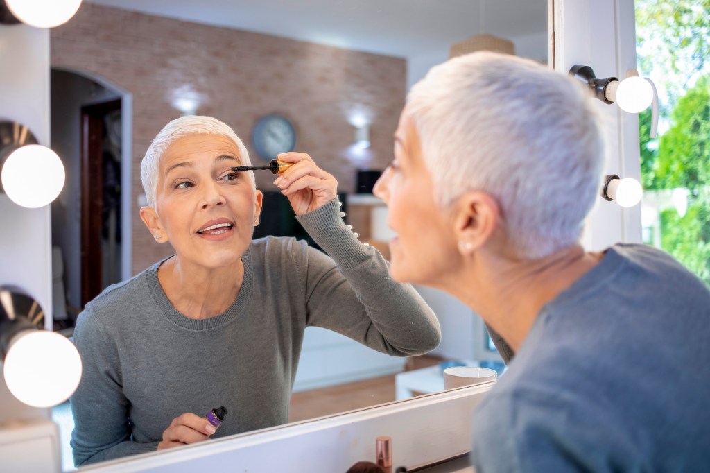 mature woman applying mascara to grow and have longer lashes