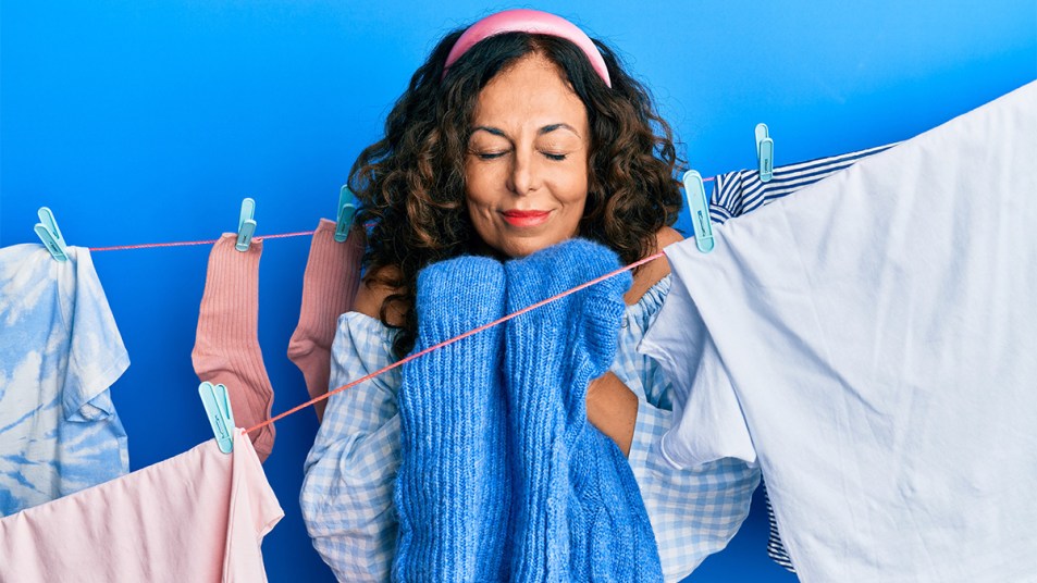 Woman doing laundry smelling scent from clean clothes
