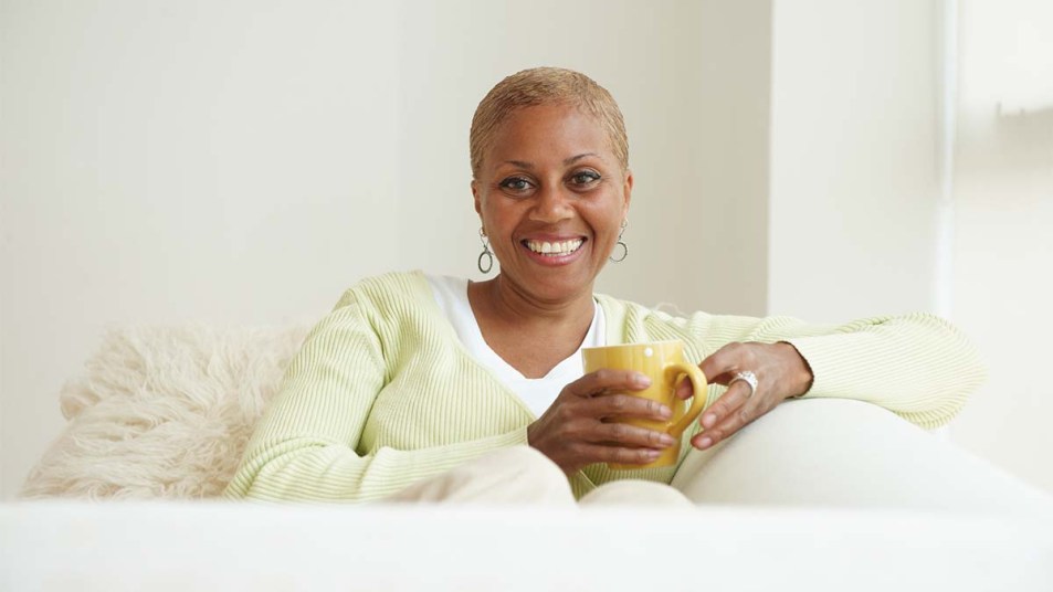 Woman sipping a hot drink on her sofa