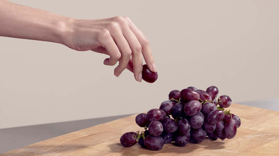 Woman taking a grape from a bunch