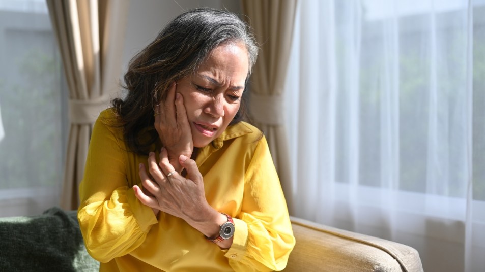 mature woman with irritated gums, holding her face in pain
