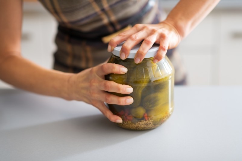 Close-up of woman opening jar of pickles