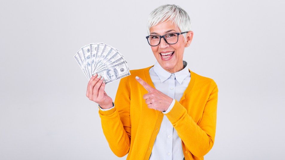 Happy senior woman holding lots of cash on a white background