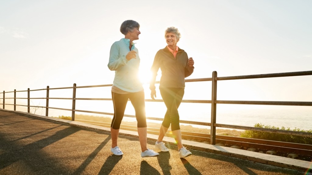 Two mature women walking together outdoors as the sun rises to get a work out done in the morning time