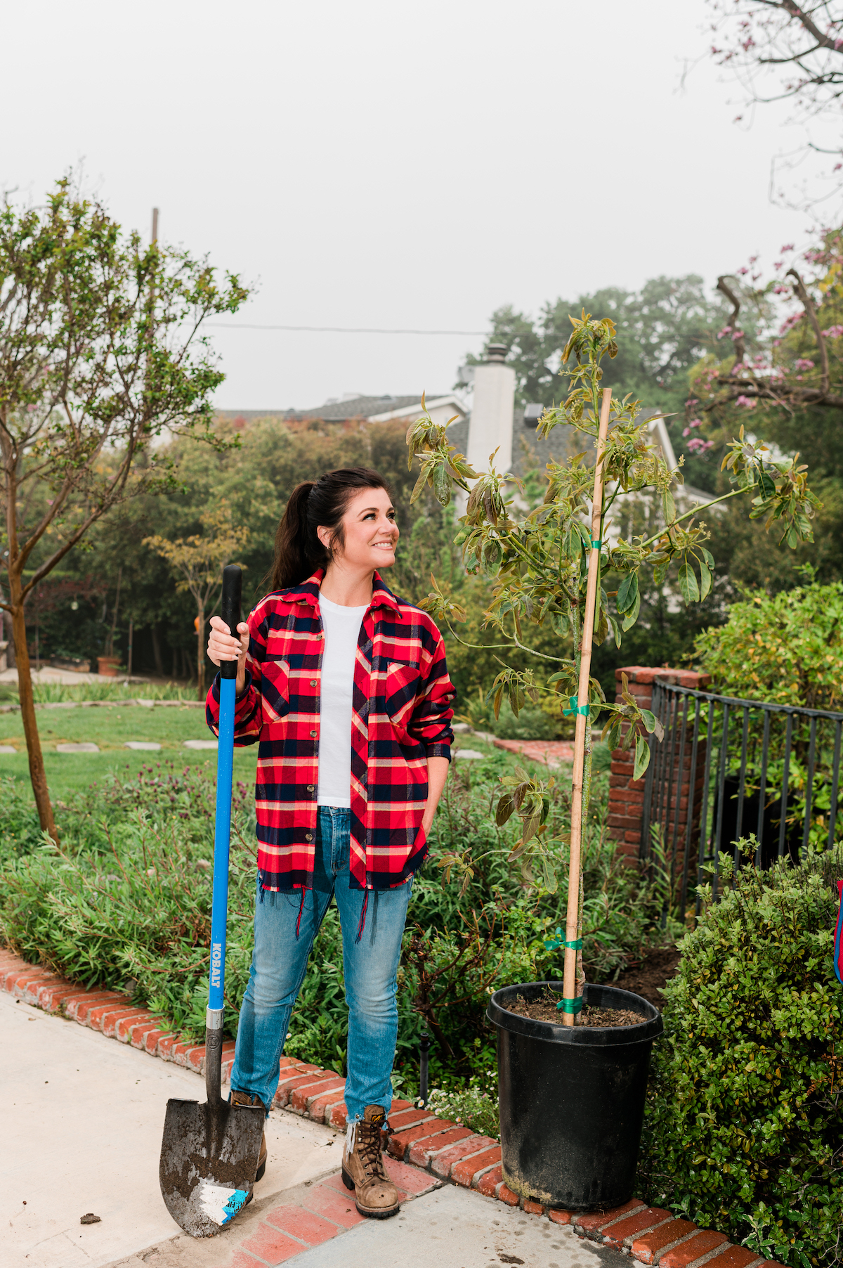 Actress Tiffani Thiessen holding shovel in garden