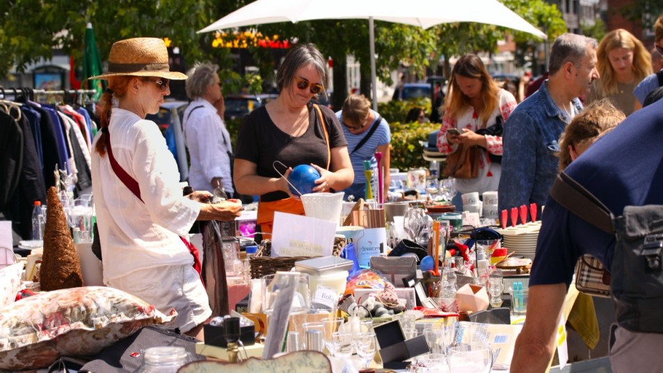 crowded yard sale with items on a table, people browsing
