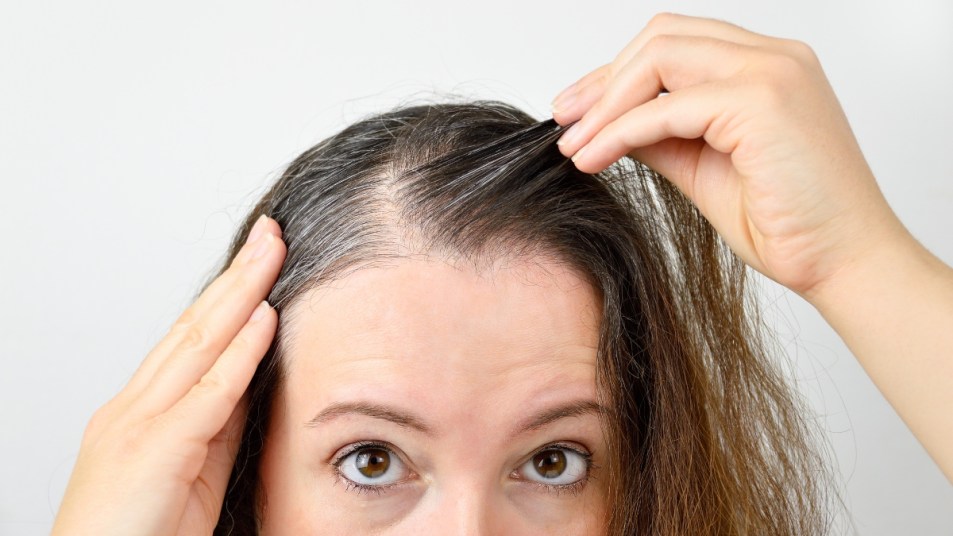 mature woman examining gray hairs, dull hair, hair color concept