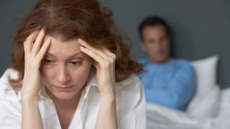 mature woman dealing with secondhand stress, husband behind her