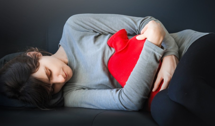 Woman using a heating pad for period pain