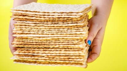 Woman's hands holding matzo against yellow background