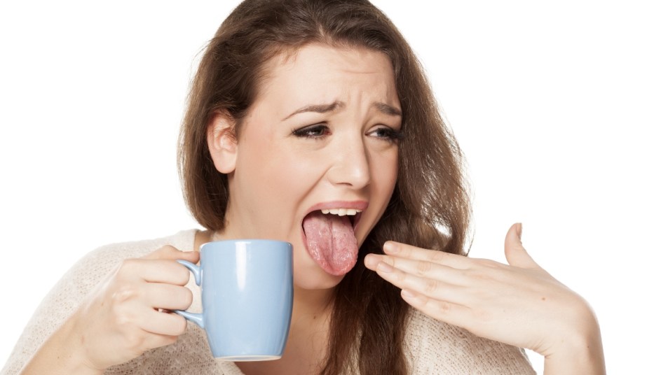woman holding blue mug who burned tongue on hot beverage