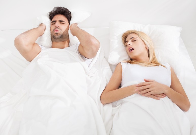 Man is trying to fall a sleep while woman is snoring