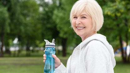 A happy older woman holding a motivational water bottle