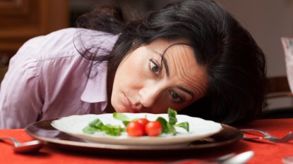 Woman looking to a little salad is tired about diet.