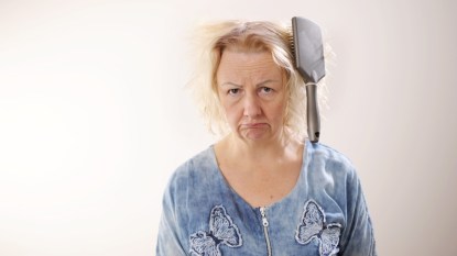 mature woman with hairbrush stuck in tangled hair